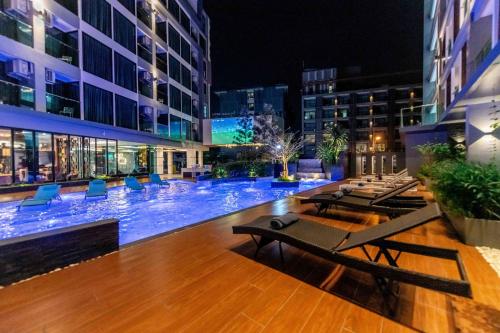 a swimming pool with tables and chairs in a building at The Proud Hotel Pattaya - SHA Certified in Pattaya North