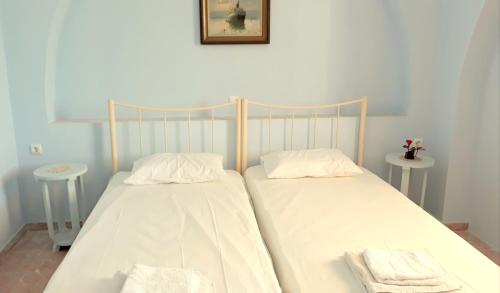a bedroom with two beds with white sheets and towels at Isavella's Apartment in Schinoussa