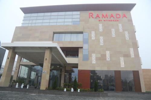 a building with a sign on the side of it at Ramada by Wyndham Aligarh GT Road in Alīgarh
