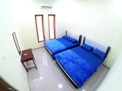 two beds in a room with blue sheets and a table at South City Homestay in Wirokerten in Bantul