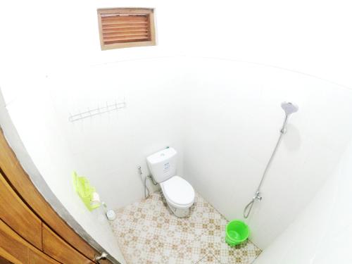 a small bathroom with a toilet and a green bucket at South City Homestay in Wirokerten in Bantul