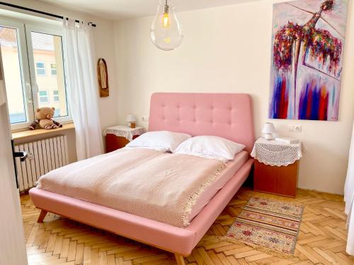 a pink bed in a bedroom with a painting at Chyža retro apartmán in Prievidza
