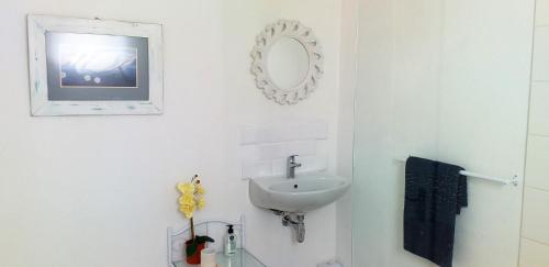 Baño blanco con lavabo y espejo en Weavers' Cottage, en Gordonʼs Bay