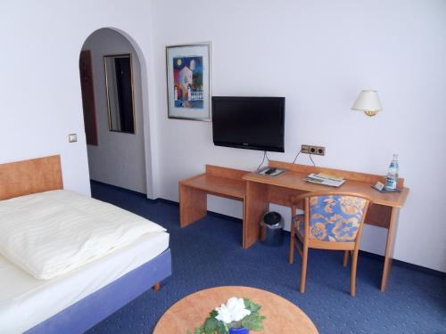 Zimmer mit einem Schreibtisch, einem Bett und einem Computer in der Unterkunft Hotel Stadt Homburg in Homburg