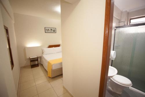 a bathroom with a bed and a toilet and a shower at Láparos Hotel in São Carlos