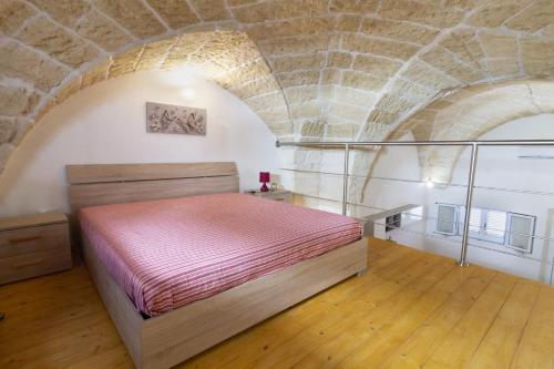 1 dormitorio con cama y pared de piedra en Case vacanza Assunta a Melendugno, en Melendugno