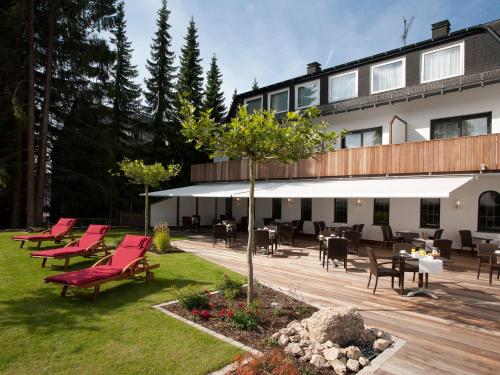 a patio with red chairs and tables in front of a building at AVITAL Resort in Winterberg
