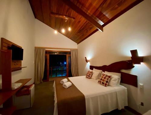 a bedroom with a bed with white sheets and a tv at Hotel Casa do Mar in Icapuí