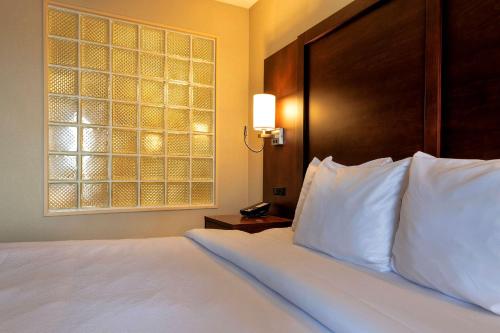 a bedroom with a bed with white pillows and a window at Comfort Suites Goodyear-West Phoenix in Goodyear
