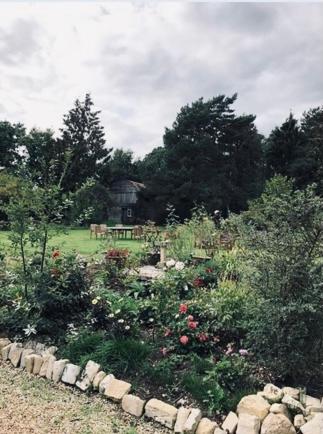 a garden with flowers and a barn in the background at Leygreen Farmhouse B&B in Beaulieu