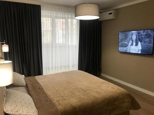 um quarto com uma cama e uma televisão de ecrã plano em Стильная однокомнатная квартира в г.Алматы em Almaty