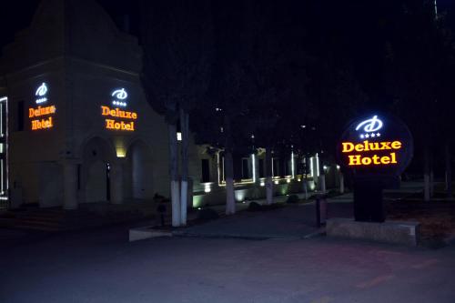 a couple of buildings with neon signs in the dark at Deluxe Hotel Ganja in Ganja