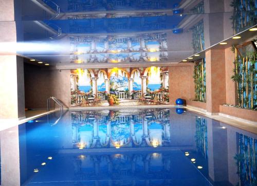 una piscina con mesas y sillas en un edificio en Deluxe Hotel Ganja, en Ganja