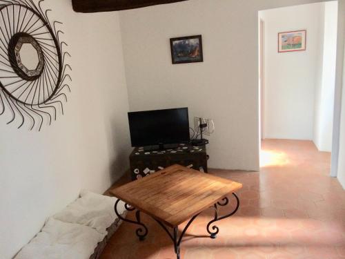 ein Wohnzimmer mit einem Tisch und einem TV in der Unterkunft LA MAISON D’ALICE in Sault-de-Vaucluse