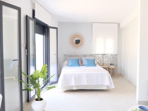 a white bedroom with a bed with blue pillows at Los Balcones Largos in Écija