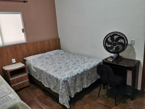 een slaapkamer met een bed en een ventilator op een tafel bij Suíte Capitólio in Capitólio