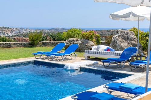 a swimming pool with blue chairs and an umbrella at Villa Odyssia in Agios Nikolaos