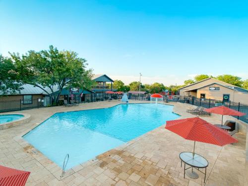 a large swimming pool with umbrellas and a person in the background at Sun Retreats Texas Hill Country in New Braunfels