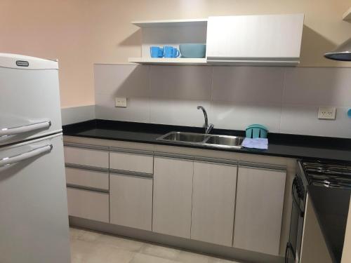 a kitchen with a sink and a refrigerator at Arenas- Departamento de playa in Puerto Madryn