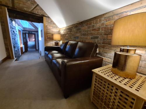a living room with a leather couch and a brick wall at Ty Morgan's in Rhayader