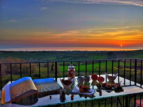 einen Tisch mit Essen auf dem Balkon mit Blick auf den Sonnenuntergang in der Unterkunft Live Your Dream in San Costanzo