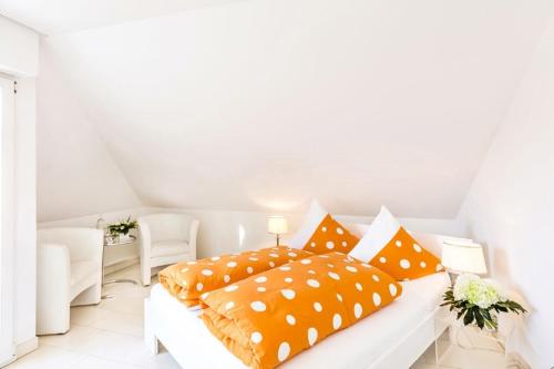 a white bedroom with orange pillows on a white bed at Hotel Villa Falkenberg in Düsseldorf