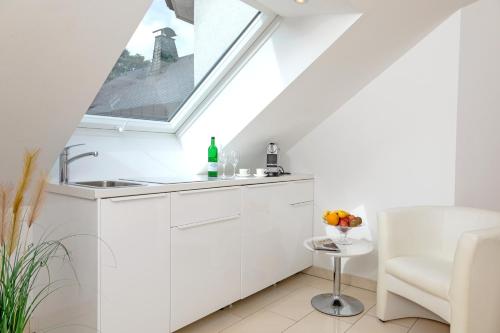 a white kitchen with a sink and a window at Hotel Villa Falkenberg in Düsseldorf