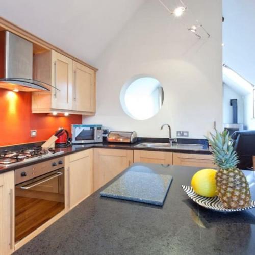 a kitchen with a pineapple and a bowl of fruit on a counter at Mews Cottage Bangor in Bangor