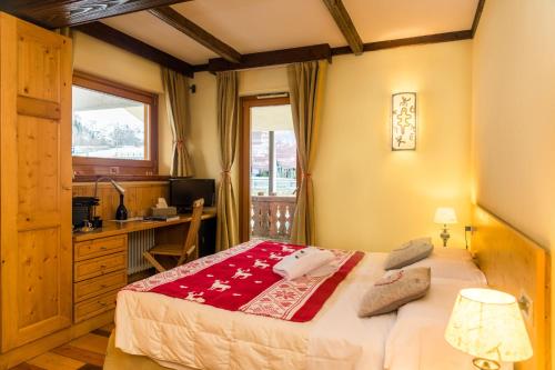 a bedroom with a bed and a desk and a window at Shatush Hotel in Courmayeur