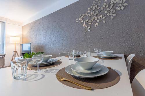 a white table with plates and glasses on it at CATTENOM NEW NOVÝ NOWY НОВИЙ - 3 min Parking, Wi-Fi, Nespresso - Repos assuré, calme & confort - Rest guaranteed, quiet & comfy in Hayange