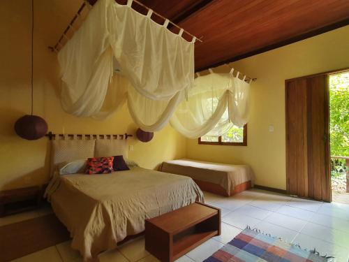 1 dormitorio con 1 cama con cortinas y ventana en Vila Esperança, en Vale do Capao