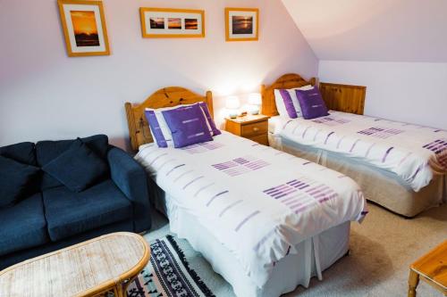 a bedroom with two beds and a blue couch at Pentigili in St. Davids