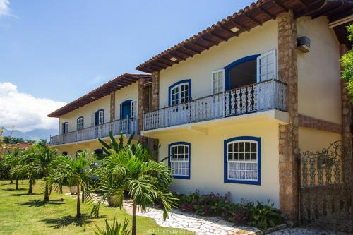 a yellow house with blue windows and palm trees at Pousada Eclipse Paraty in Paraty