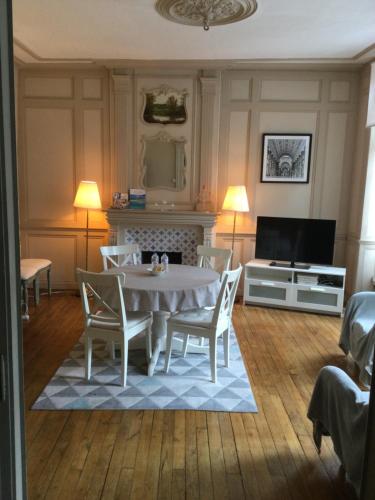 sala de estar con mesa, sillas y TV en EGLANTINE APPARTEMENT CENTRE HISTORIQUE DE DINAN, en Dinan