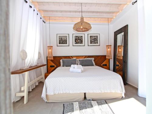 1 dormitorio con cama blanca y lámpara de araña en Enalion Suites, en Mykonos ciudad