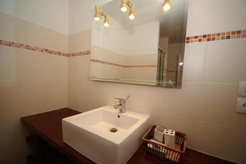 La salle de bains est pourvue d'un lavabo blanc et d'un miroir. dans l'établissement La Grange, à Maisons