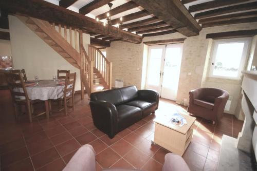 un salon avec un canapé en cuir noir et une table dans l'établissement La Grange, à Maisons