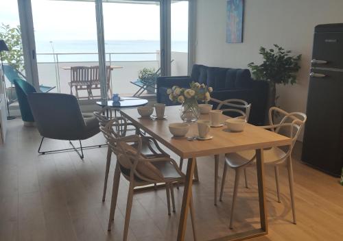a dining room table with chairs and a table with flowers on it at LE 21 Vue sur Mer in Concarneau