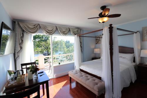 ein Schlafzimmer mit einem Himmelbett und einem Fenster in der Unterkunft Lipton Place by Elegant Waterfront in Victoria