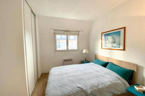 Un dormitorio con una cama con almohadas azules y una ventana en Logement 4 lits en plein coeur de Cabourg en Cabourg