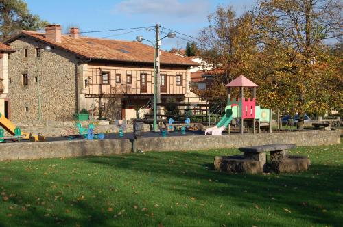 a park with a playground with a bench in the grass at La Casona de Revolgo in Santillana del Mar