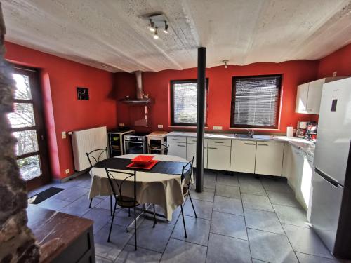 une cuisine aux murs rouges et une table avec des chaises dans l'établissement L'Ancienne Forge - Gîte à la ferme, à Sainte-Marie