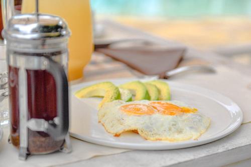 an egg on a plate with bananas and a drink at Kobe Suite Resort in Watamu