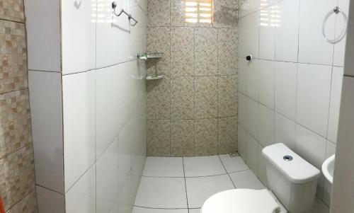 La salle de bains blanche est pourvue d'une douche et de toilettes. dans l'établissement Aconchego em Parnaiba jw, à Parnaíba