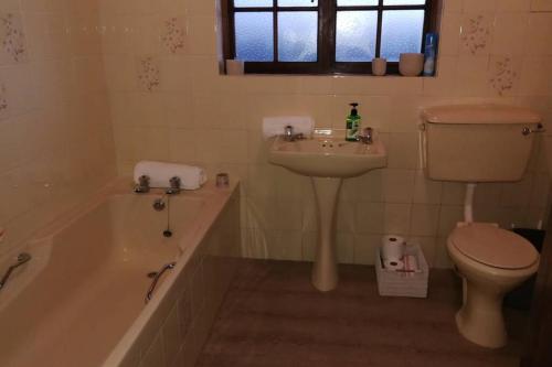 a bathroom with a tub and a sink and a toilet at WitsEnd Almost Heaven in St Francis Bay