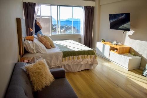 a bedroom with a bed and a window and a couch at Patagonia D.A.T in San Carlos de Bariloche