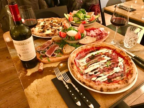 a table with three pizzas and a bottle of wine at Hotel Alpina Luzern in Luzern