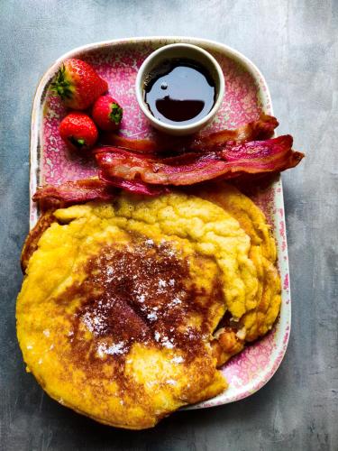 a plate of pancakes with bacon and a side of strawberries at The Lodges @ Barra Castle in Inverurie