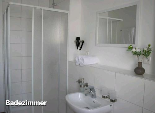 Baño blanco con lavabo y espejo en Gästehaus Traunreut - Monteur und Gästezimmer -, en Traunreut