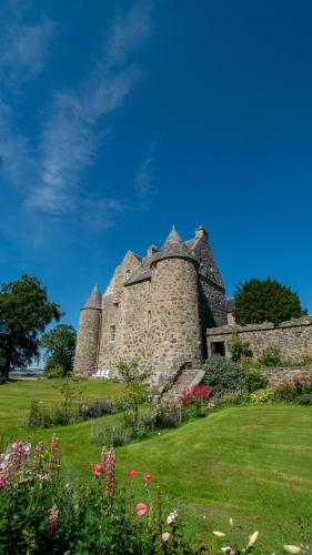 an old castle on a field with flowers at The Lodges @ Barra Castle in Inverurie